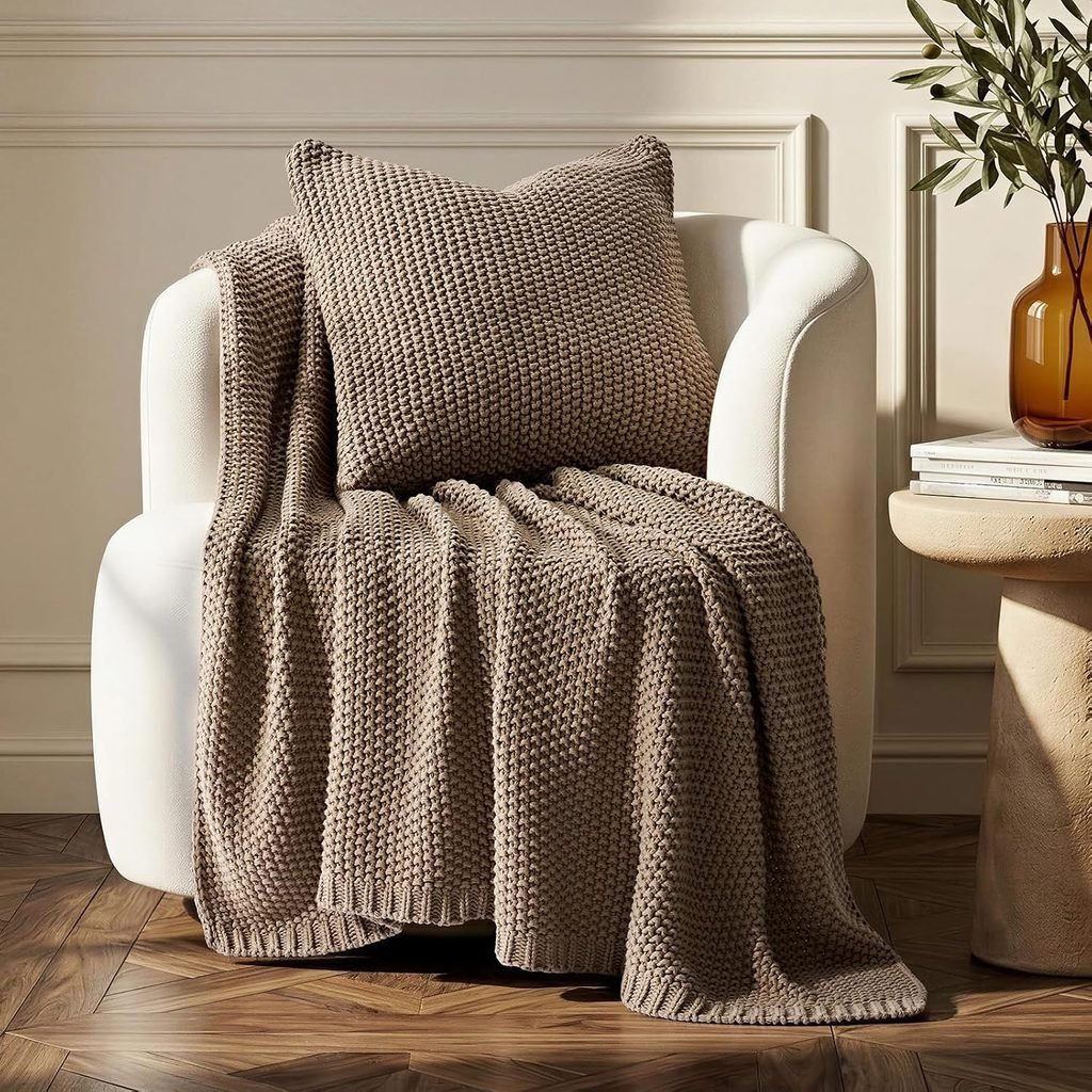 Warm taupe knit throw blanket draped over a cream accent chair